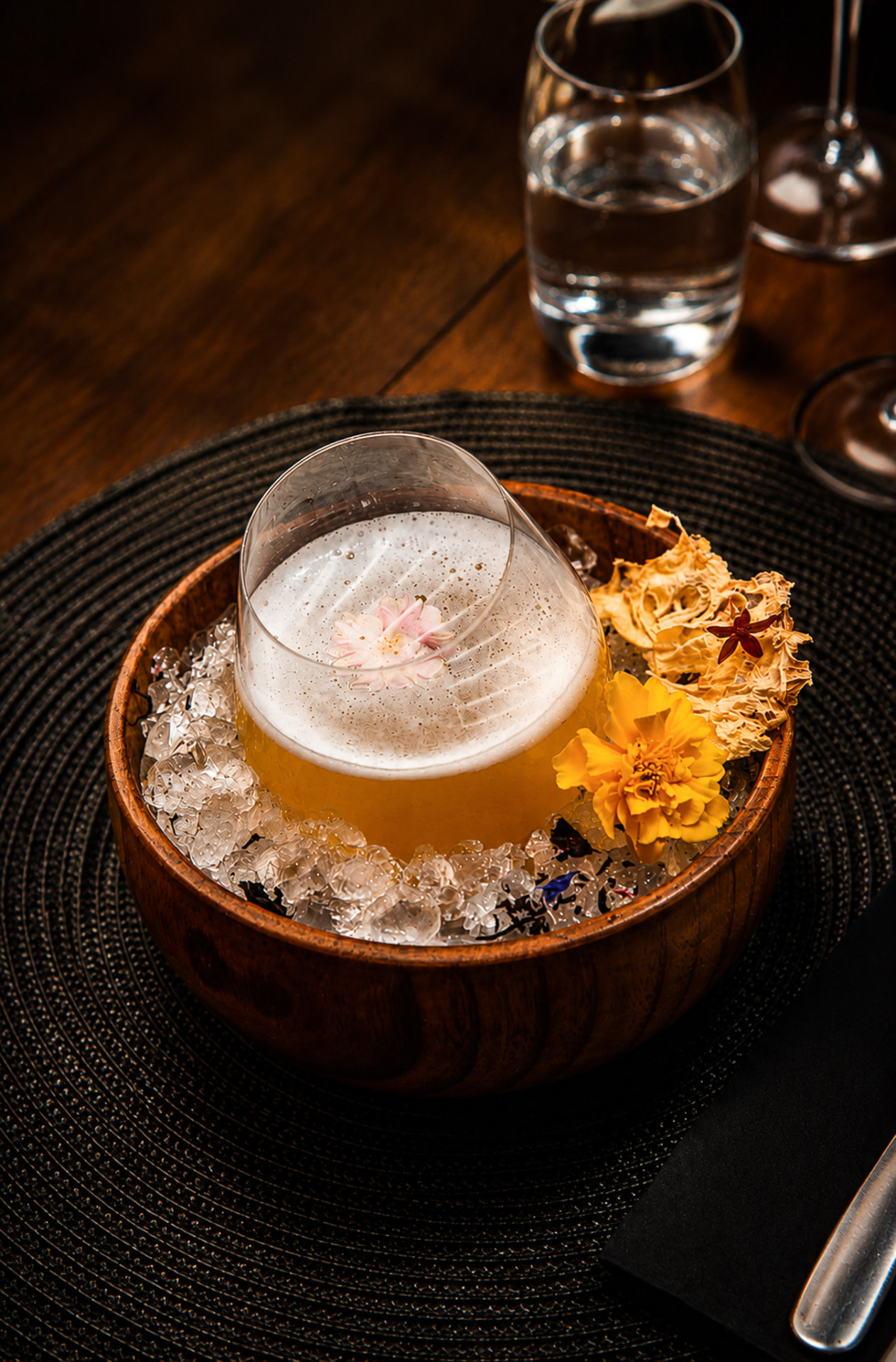 Cocktail signature servi sur glace pilée et fleurs